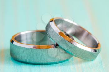 Two white gold rings on the blue wooden surface