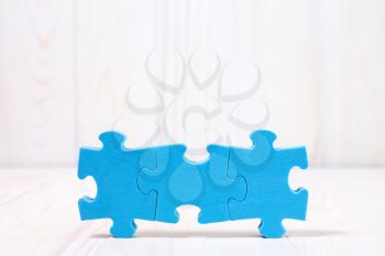 Three puzzle pieces on white wooden background. With copy-space for text