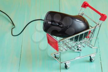 Shopping cart with a computer mouse on blue background