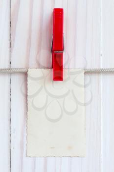 Photo frame hanging on a rope over white wooden background