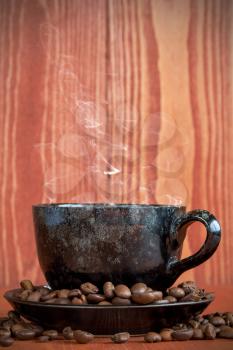 Small cup of black coffee on a brown background with coffee beans