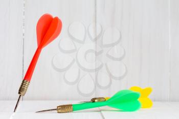 Three color darts on a white wooden background