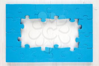 Blue puzzle frame on white wooden background