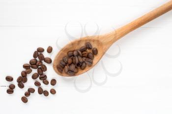 Coffee crop beans on a spoon and wooden background