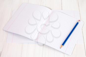 New exercise books and pencil on white wooden surface