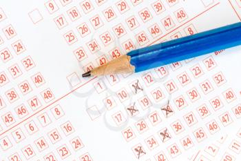 Pencil and lottery ticket with ticked numbers
