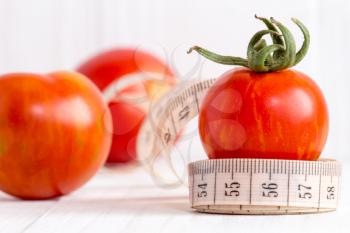 Healthy lifestyle concept with measuring tape and red tomato fruits