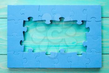 Jigsaw puzzle frame on blue wooden background