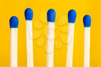Row of five matchsticks on yellow background