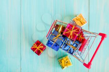 Cart full of colorful gifts on blue wooden background