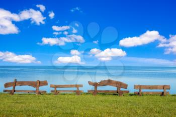 Four wooden benches in front of the sea with blue sky