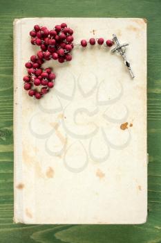 Old book and rosary on dark wood planks background