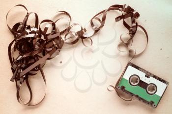 Audio cassette with pulled out tape on stained paper background. Copy-space.