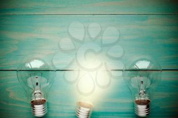 Glow among other lightbulb on a wooden background