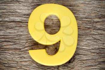 Yellow number nine on the wooden background