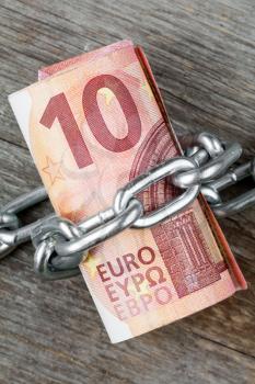 Ten euro bills with chain , concept money tied up