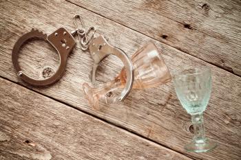 Two empty glasses and handcuffs, alcoholism concept