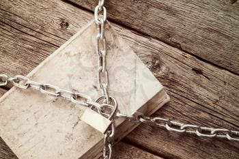 Old book with chain and padlock on wooden background.Vintage style.