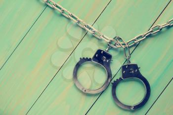  Handcuffs hanging on the chain against wooden background.Filtered image.