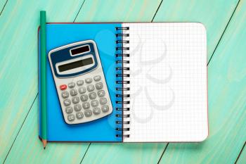 Electronic calculator and open notebook with squared sheet for copy-space
