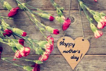 Heart shaped mothers day card with carnations on wood background
