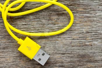  Yellow USB cable on wooden background- top view