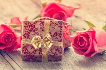 Open gift box and roses on a wooden background
