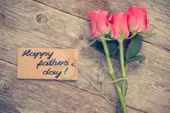 Father's day card with roses on old wooden board.