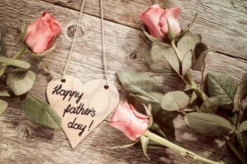 Heart shaped father's day card with red roses on wooden background