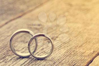 Soft pastel image with wedding rings on wooden background