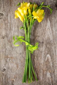 Bouquet  of yellow freesias on old wooden background
