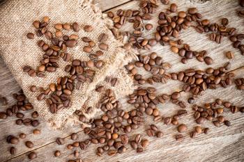  Piece of  burlap  with roasted coffee beans on wooden background