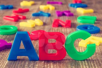  ABC spelling and pile of colorful plastic letters on wooden background