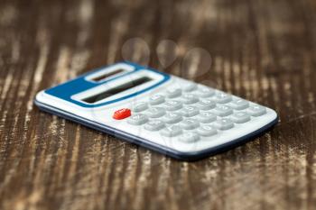 Electronic calculator on wooden background. Selective focus.