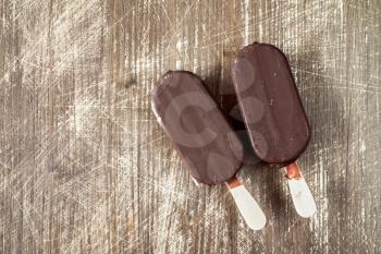 Ice cream covered with chocolate  on wooden background with copy-space