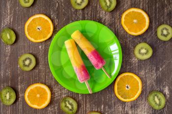 Popsicles with sliced fruits on dark wooden background. Summer food concept. Top view.