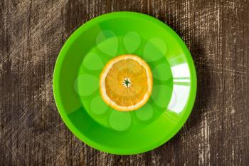 Orange slice in a green plate, top view