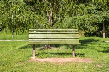 Empty wooden bench in a park for a hiker or casual walker to sit and rest.