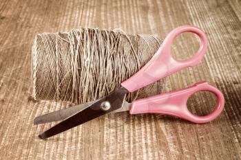 Scissors and skein jute twine on the wooden background