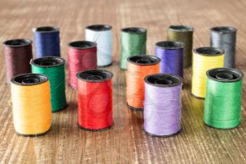Bobbins with colorful threads on old wooden table background