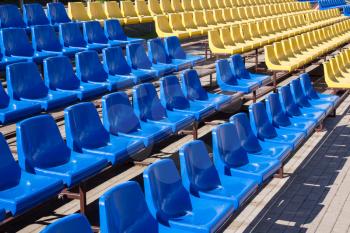 Row of blue and yellow chairs in stadium