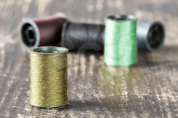  Bobbins with  threads on old wooden table background