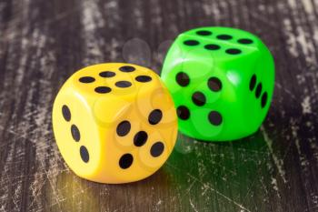 Yellow and green dices on wooden background. 