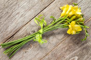   Bouquet of yellow freesias on old wooden surface
