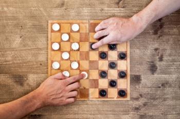 Two players starting play draughts checkers board game