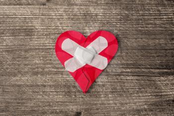  Broken heart with plaster on the old wooden background