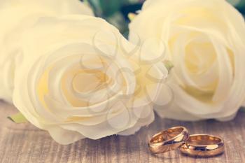 Wedding rings with white roses on background