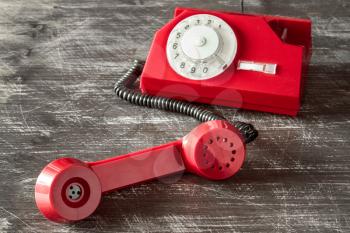Red vintage phone with rotary dial on the wooden background