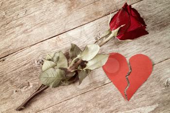 Divorce concept - red broken heart with old rose on wooden background