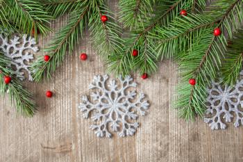 Wooden background with fir branch and silver snowflakes